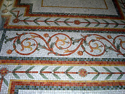 [The floor is comprised of small mosaic tiles fashioned into intricate designs. Individual tiles are shades of green, white, red, and orange.]